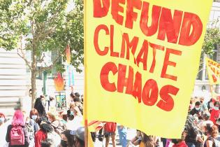Image of a banner/flag with the words "Defund Climate Change" painted on it