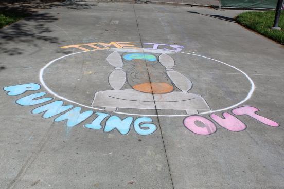 sidewalk chalk art displaying hourglass and words time is running out