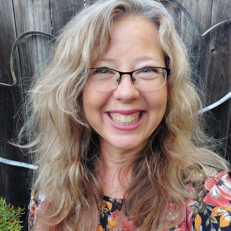 photo of person with long blond hair, glasses and floral print top