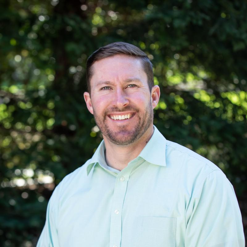 image of person with brown head and facial hair smiling at camera