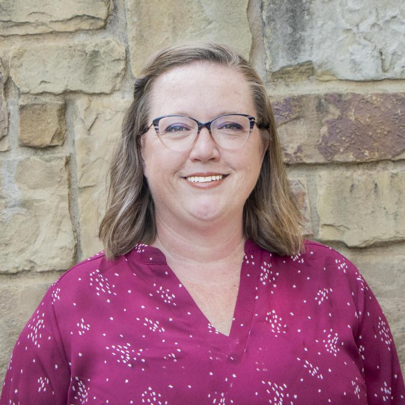 photo op person with glasses, shoulder length hair and magenta top