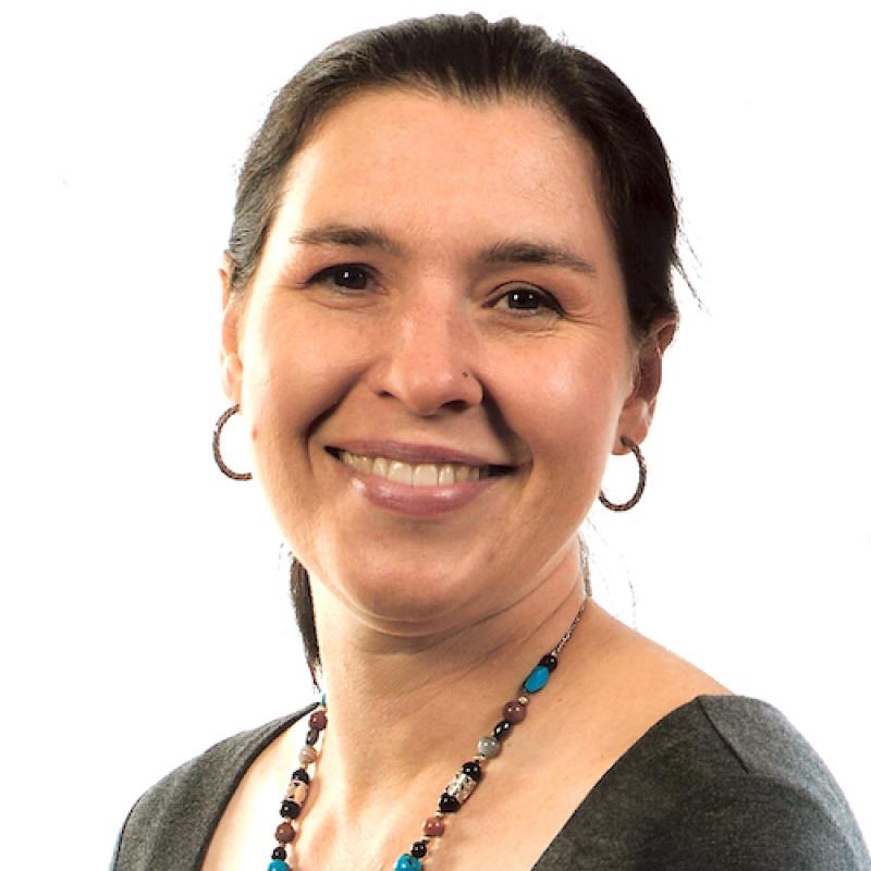 photo of person with brown hair pulled back, wearing hoop earrings and beaded necklace