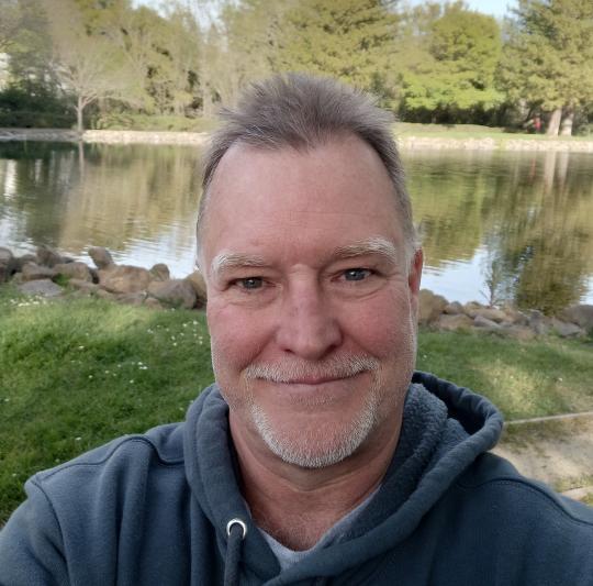 Middle aged man standing in front of a body of a water